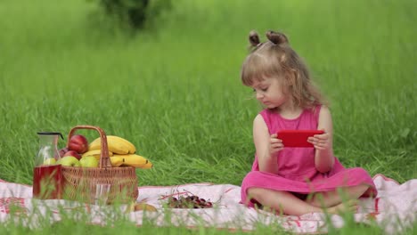 Weekend-at-picnic.-Girl-on-grass-meadow-play-online-games-on-mobile-phone.-Social-network,-chatting