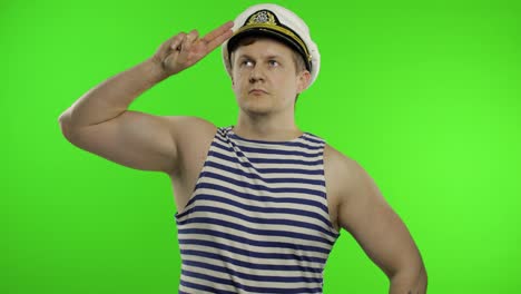 Young-sailor-man-salutes-with-hand,-looking-up.-Seaman-guy-in-sailor's-vest