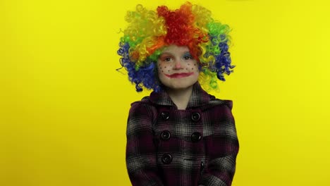 Little-child-girl-clown-in-colorful-wig-making-silly-faces,-looks-with-eyes-in-different-directions