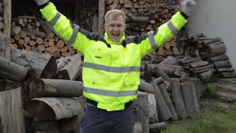 Lumberjack-in-reflective-jacket.-Man-woodcutter-dancing,-celebrate.-Sawn-logs,-firewood-background