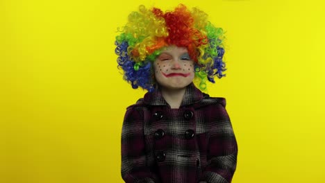 Little-caucasian-child-girl-clown-in-rainbow-wig-making-silly-faces,-hakes-her-head.-Halloween