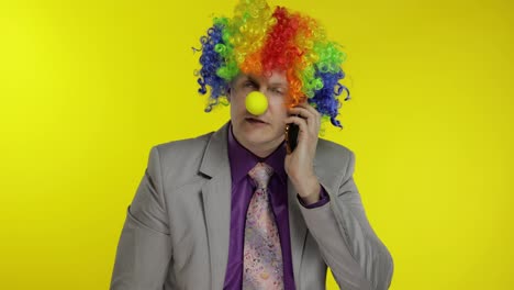 Clown-Geschäftsmann-Unternehmer-Chef,-Der-Am-Mobiltelefon-Spricht.-Gelber-Hintergrund