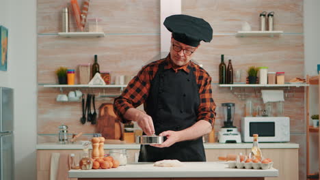 Baker-with-bonete-and-kitchen-apron-using-metallic-sieve