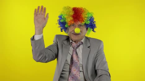 Senior-elderly-clown-businessman-entrepreneur-in-wig-waves-his-hands,-smiling