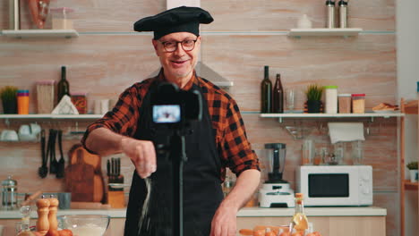 Portrait-of-positive-chef-recording-vlog-in-kitchen