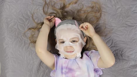 Teen-girl-applying-moisturizing-face-mask.-Child-kid-take-care-of-skin-with-cosmetic-facial-mask