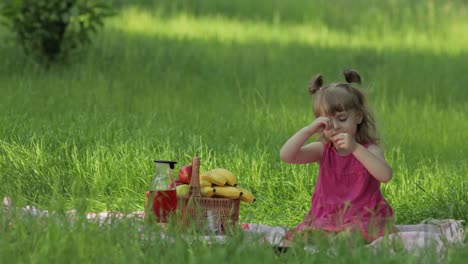 Weekend-at-picnic.-Lovely-caucasian-child-girl-on-green-grass-meadow-eating-merry,-cherry