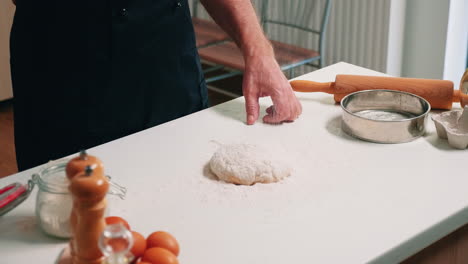 Baker-pouring-flour-on-dough-for-bread