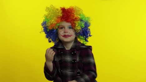 Little-child-girl-clown-in-rainbow-wig-making-silly-faces.-Having-fun,-smiling,-dancing.-Halloween