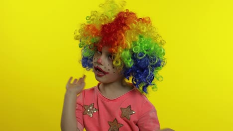 Little-child-girl-clown-in-rainbow-wig-making-silly-faces.-Fool-around,-smiling,-dancing.-Halloween