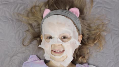 Teen-girl-applying-moisturizing-face-mask.-Child-kid-take-care-of-skin-with-cosmetic-facial-mask