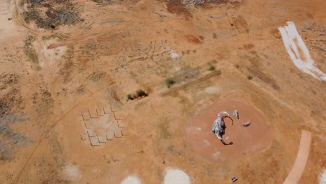 Drone-flying-over-a-strange-park-with-a-dinosaur-statue-in-the-Australian-Outback