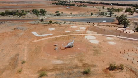 Drone-flying-around-a-strange-dinosaur-state-in-a-park-near-the-road-in-the-Australian-Outback