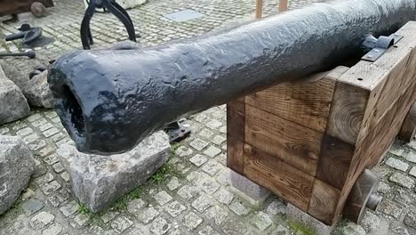 Wrought-iron-wood-mounted-artillery-cannon-displayed-on-Holyhead-harbour-cobblestone-pavement