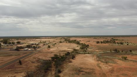 Drohne-Steigt-über-Eine-Verlassene-Landschaft-Auf-Und-Zeigt-Eine-Sehr-Kleine-Australische-Outback-Stadt