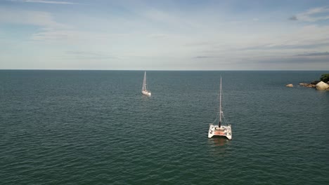 Drone-captures-of-a-yacht-and-boats-cruising-through-the-calm-sea-water-near-the-rocky-shore