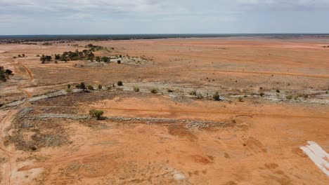 Drohne-Steigt-Herab-Und-Fährt-Dann-Rückwärts-über-Einen-Seltsamen-Outback-Park,-Der-Eine-Dinosaurierstatue-Zeigt