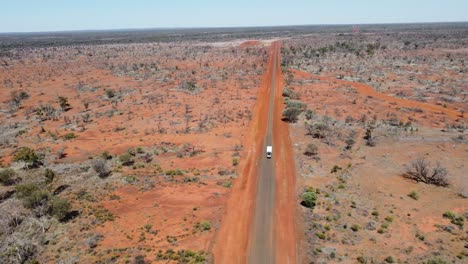 Luftaufnahme-Einer-Asphaltierten-Landstraße,-Während-Ein-Auto-Mit-Einem-Wohnwagen-Im-Australischen-Outback-Vorbeifährt