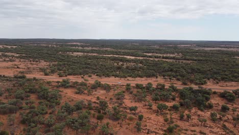 Drohne-Steigt-über-Ein-Kesselgrundstück-Auf-Und-Bewegt-Sich-Vorwärts-In-Richtung-Einer-Landstraße-Und-Einem-Geparkten-Weißen-Auto-Im-Australischen-Outback