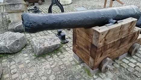 Wrought-iron-wood-mounted-artillery-cannon-displayed-on-British-cobblestone-pavement