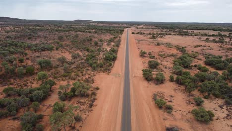 Drone-Descendiendo-Sobre-Una-Carretera-Rural-Muy-Estrecha-Y-Sellada-En-El-Interior-De-Australia