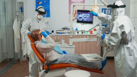 Dentist-in-protection-suit-examining-teeth-with-medical-instruments