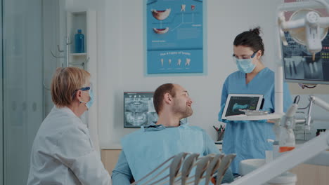Zahnärzteteam-Erklärt-Kranken-Patienten-Die-Röntgenaufnahme