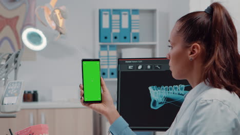 Close-up-of-orthodontist-holding-smartphone-with-green-screen
