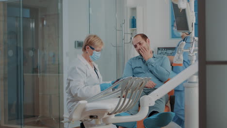 Dentista-Mirando-Radiografías-Dentales-Y-Consultando-A-Un-Paciente-Con-Dolor-De-Muelas