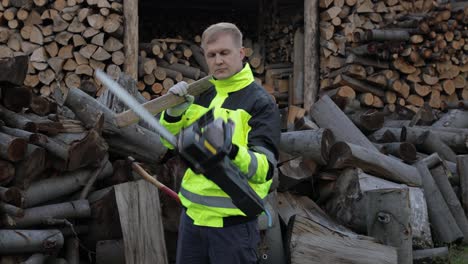 Lumberjack-worker.-Man-woodcutter-holds-big-axe-and-electric-chainsaw-on-his-hands.-Firewood