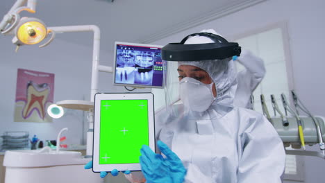 Doctor-in-ppe-suit-showing-tablet-with-green-screen