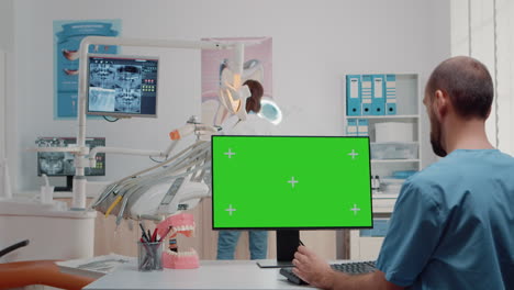 Dental-assistant-using-monitor-with-horizontal-green-screen