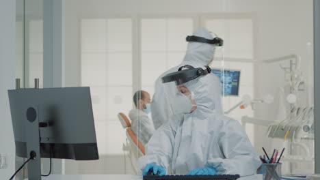 Dentistry-team-of-specialists-with-ppe-suits-using-computer