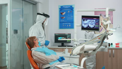 Dentist-in-coverall-showing-patient-situation-of-teeth-x-ray