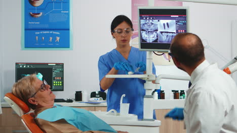 Doctor-pointing-on-digital-screen-showing-dental-implants