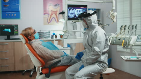 Dentist-in-protection-suit-explaining-dental-surgery-process