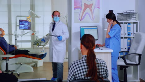 Dentist-with-protective-mask-giving-teeth-x-ray-to-nurse