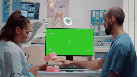 Oral-care-team-looking-at-horizontal-green-screen-on-monitor