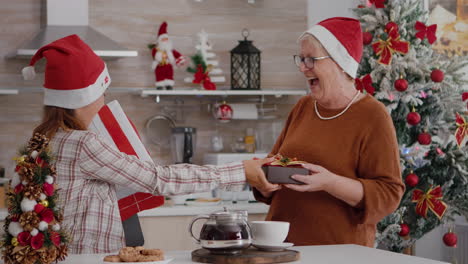Happy-family-wearing-santa-hat-surprising-each-other-with-wrapper-xmas-present-gift