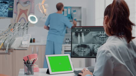 Orthodontist-using-horizontal-green-screen-on-tablet