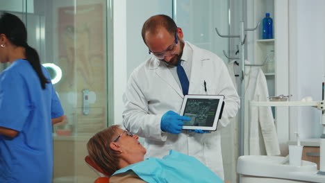 Kieferorthopäde-Nutzt-Tablet,-Um-Dem-Patienten-Zahnröntgenbilder-Zu-Erklären