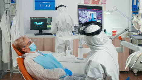 Stomatologist-in-coverall-and-patient-looking-at-digital-dental-x-ray
