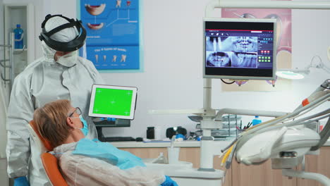 Dentist-with-face-shield-pointing-at-green-screen-display