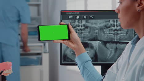 Nahaufnahme-Eines-Zahnarztes,-Der-Sein-Smartphone-Mit-Grünem-Bildschirm-Analysiert