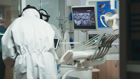 Kieferorthopäde-Im-Overall-Erklärt-Mit-Einem-Tablet-Die-Zahnärztliche-Röntgenaufnahme
