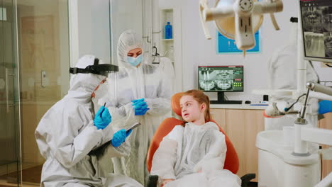 Dentist-doctor-in-coverall-talking-with-girl-patient-before-examination