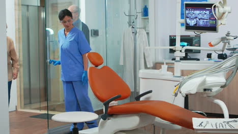 Nurse-inviting-senior-woman-in-consultation-dental-room
