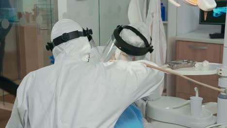 Dentists-with-face-shield-cleaning-and-examining-patient-teeth
