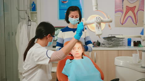 Doctor-En-Odontología-Hablando-Con-Un-Niño-Sentado-En-Una-Silla-Estomatológica