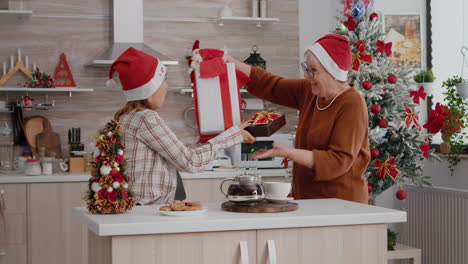 Grandmother-and-granddaughter-bringing-xmas-wrapper-present-gift-with-ribbon-on-it